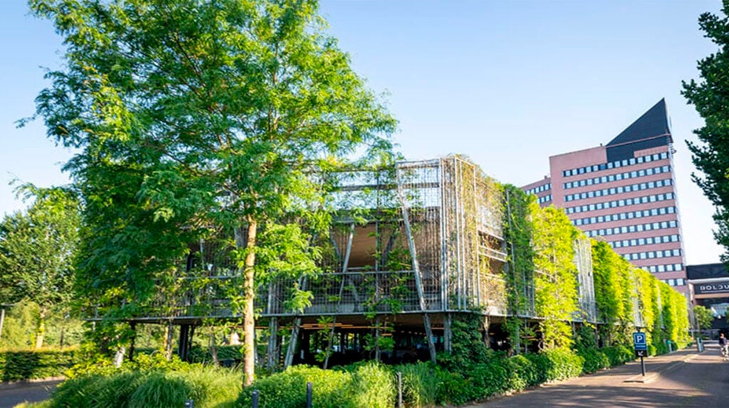 Parkeergarage met gevel volledig begroeid met klimplanten in stedelijke omgeving.