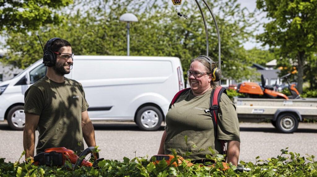 Twee idverde-medewerkers met gehoorbescherming en heggenscharen bij een pas gesnoeide heg.