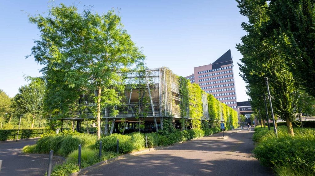 Begroeide gevel van een parkeergarage met klimplanten en groenbeplanting bij kantoorgebouw Bolduc.