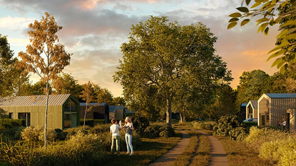 Groen ingerichte vakantiepark met beplanting rond vrijstaande huisjes en wandelpad tussen struiken en bomen.