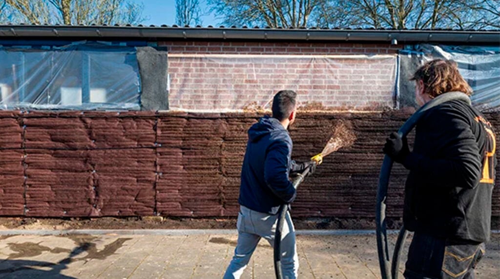 Twee medewerkers voeren verticaal hydroseeding uit op een muur bij Yuverta mbo Houten