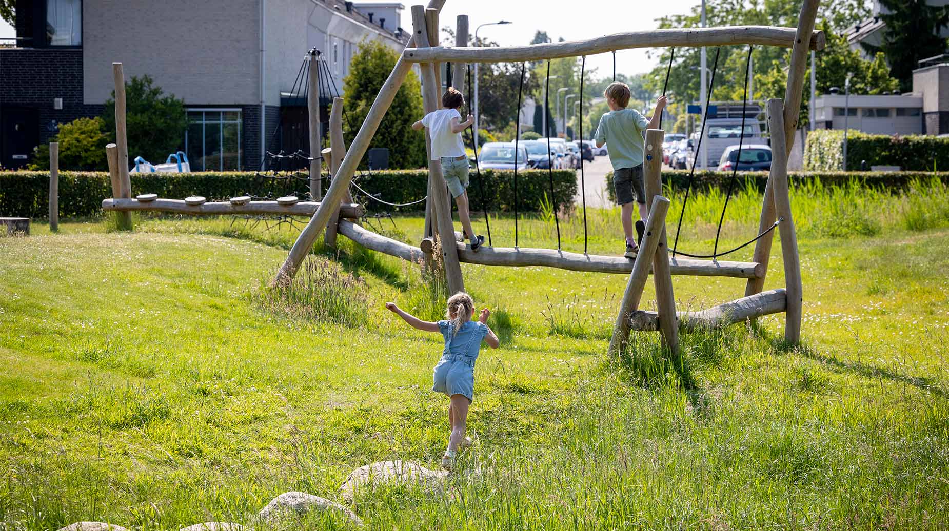 Kinderen spelen op een houten klimtoestel in een groene woonwijk in Tilburg.
